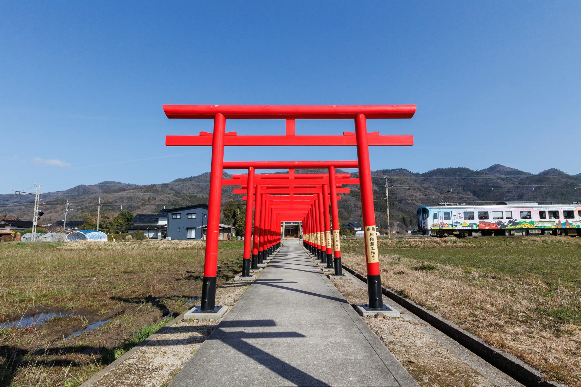 Rote Torii des Awazu-Inari-Schreins, daneben ein Zug der Ichibata-Bahn
